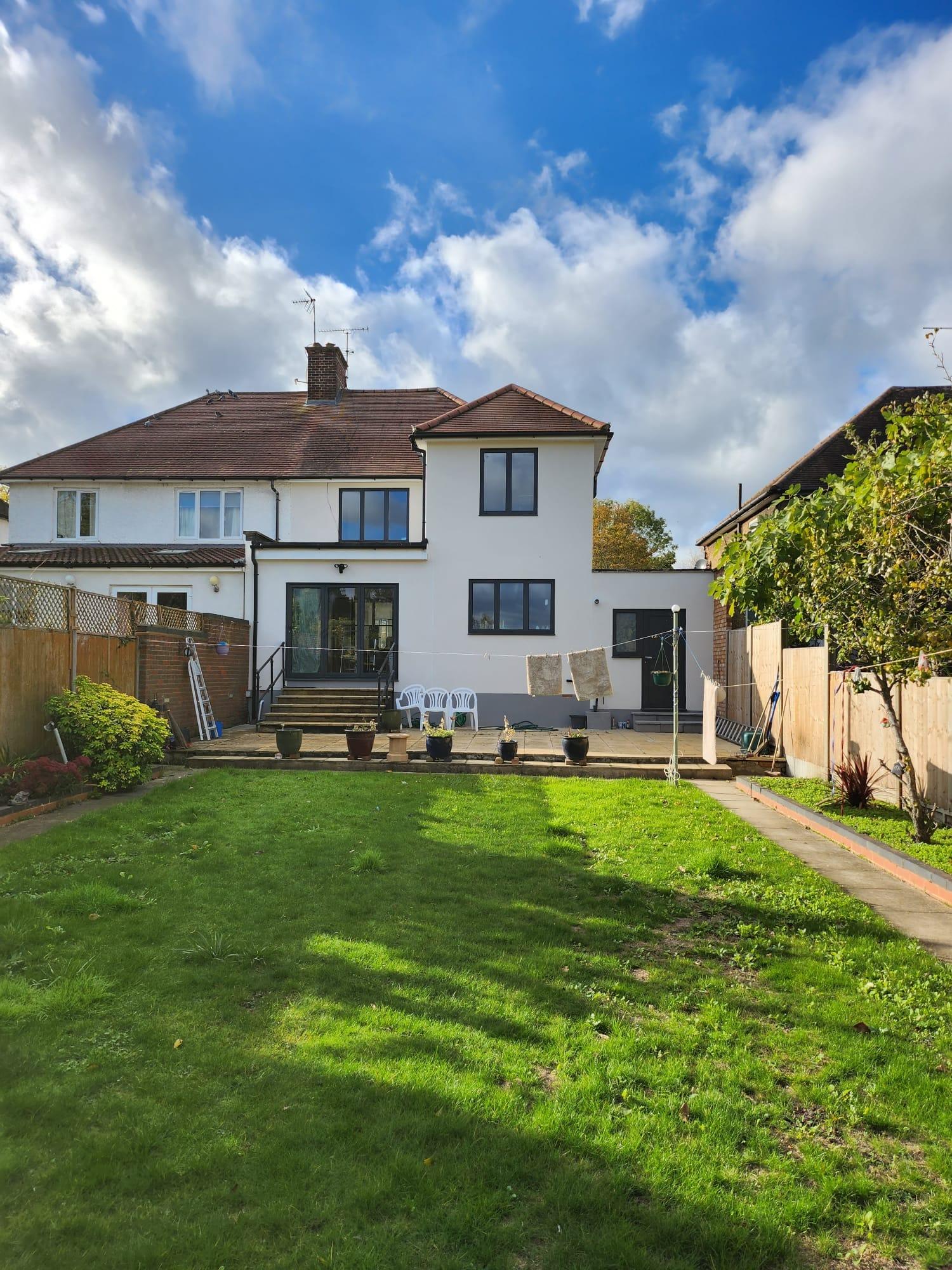 Rear garden and the back elevation of a rendered semi-detached house before work