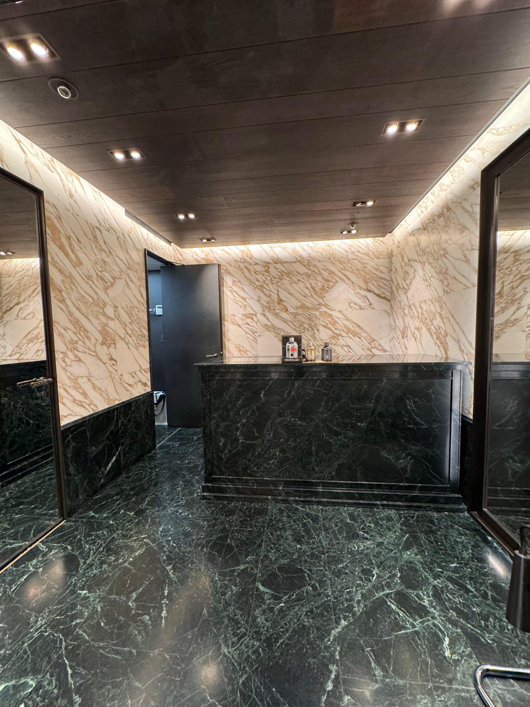 Reception lobby clad in onyx and green marble, with a stone counter and concealed lighting