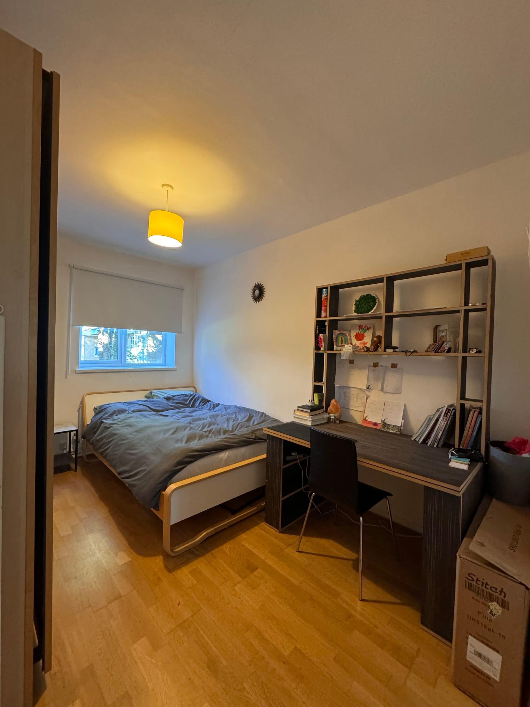 Bedroom with fitted shelving over a desk and oak flooring