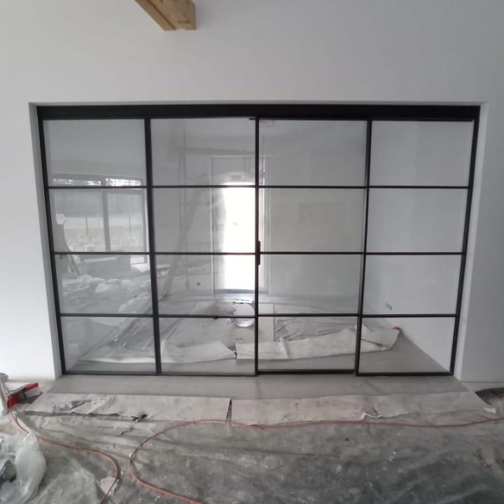 Black steel Crittall-style glazed partition newly installed, floor still sheeted