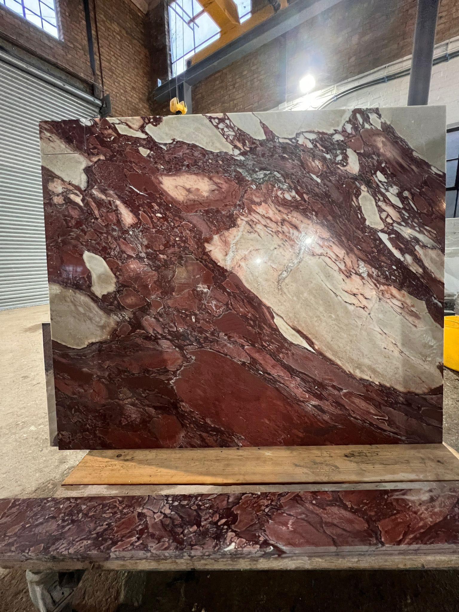 Rosso marble slab standing in a stone yard, selected for a project
