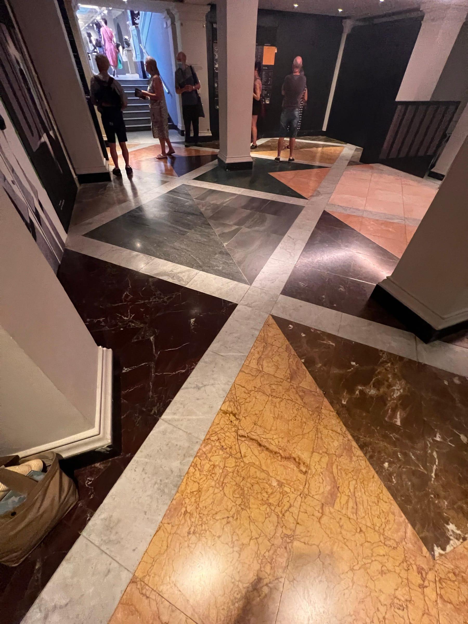 Geometric marble floor in a gallery interior, laid in white, rosso, green and sienna
