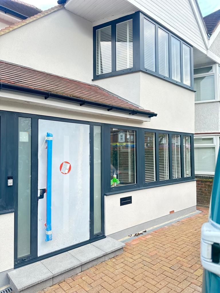 Rear elevation with a first-floor bay in anthracite aluminium glazing over a rendered ground floor