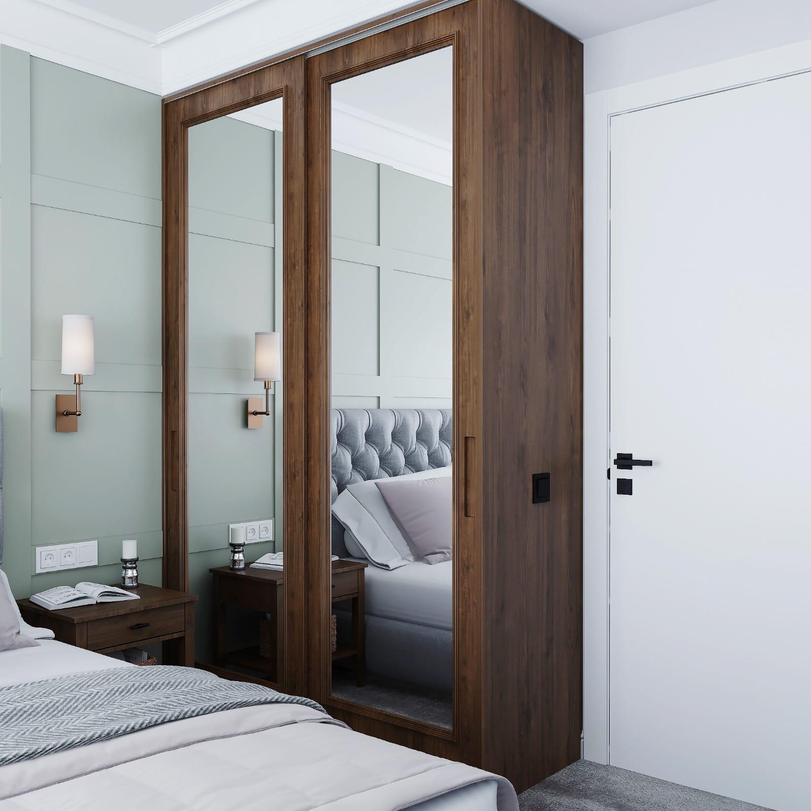 Walnut-framed mirrored wardrobe door set into sage wall panelling beside the bed