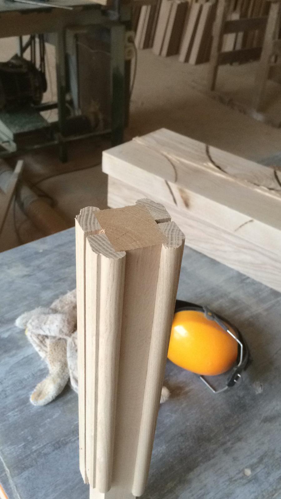 Machined timber mouldings on a workshop bench beside ear defenders