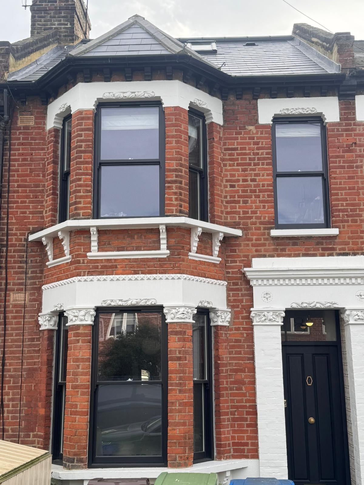 Bay-fronted Victorian terrace in red brick and stucco, with new black-framed windows