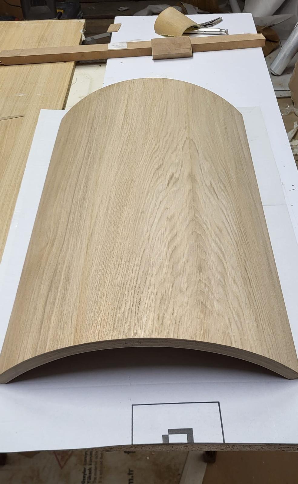 Curved oak veneer panel on the workshop bench, set out over its full-size drawing
