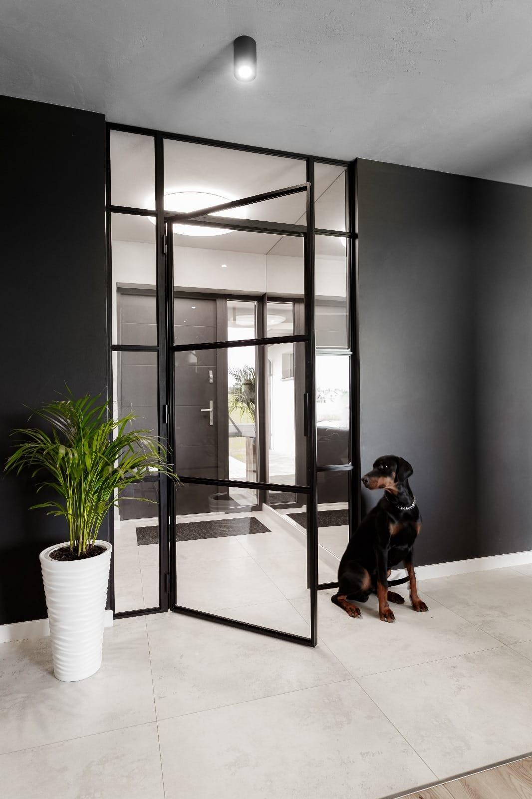 Entrance hall with black steel pivot doors in glazed panels, a planter to one side