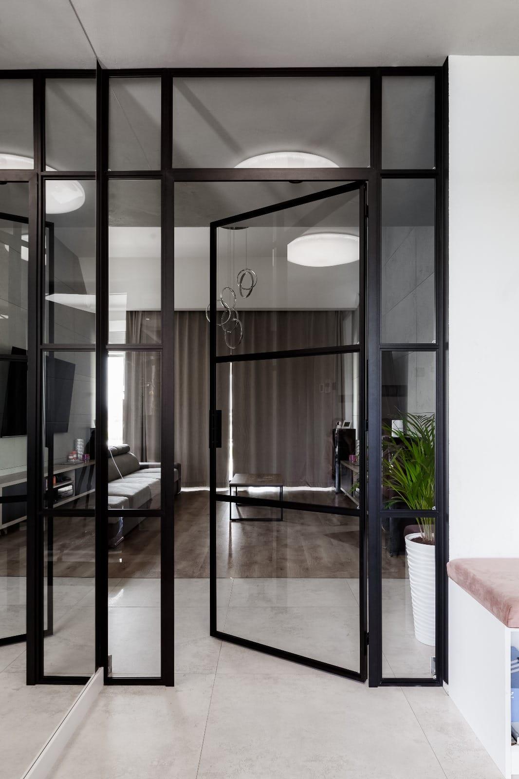 Black steel glazed double doors opening from a hall into a living room