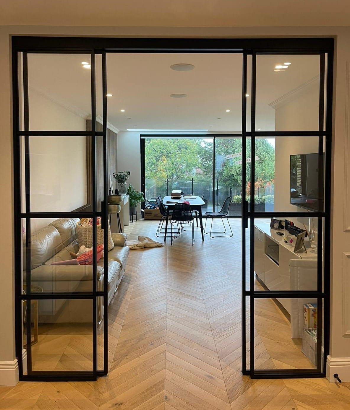 Black steel glazed double doors between a living room and a rear extension