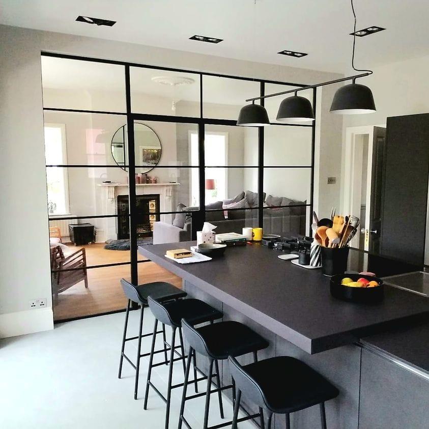 Kitchen with a black steel screen through to the living room and a breakfast bar in the foreground