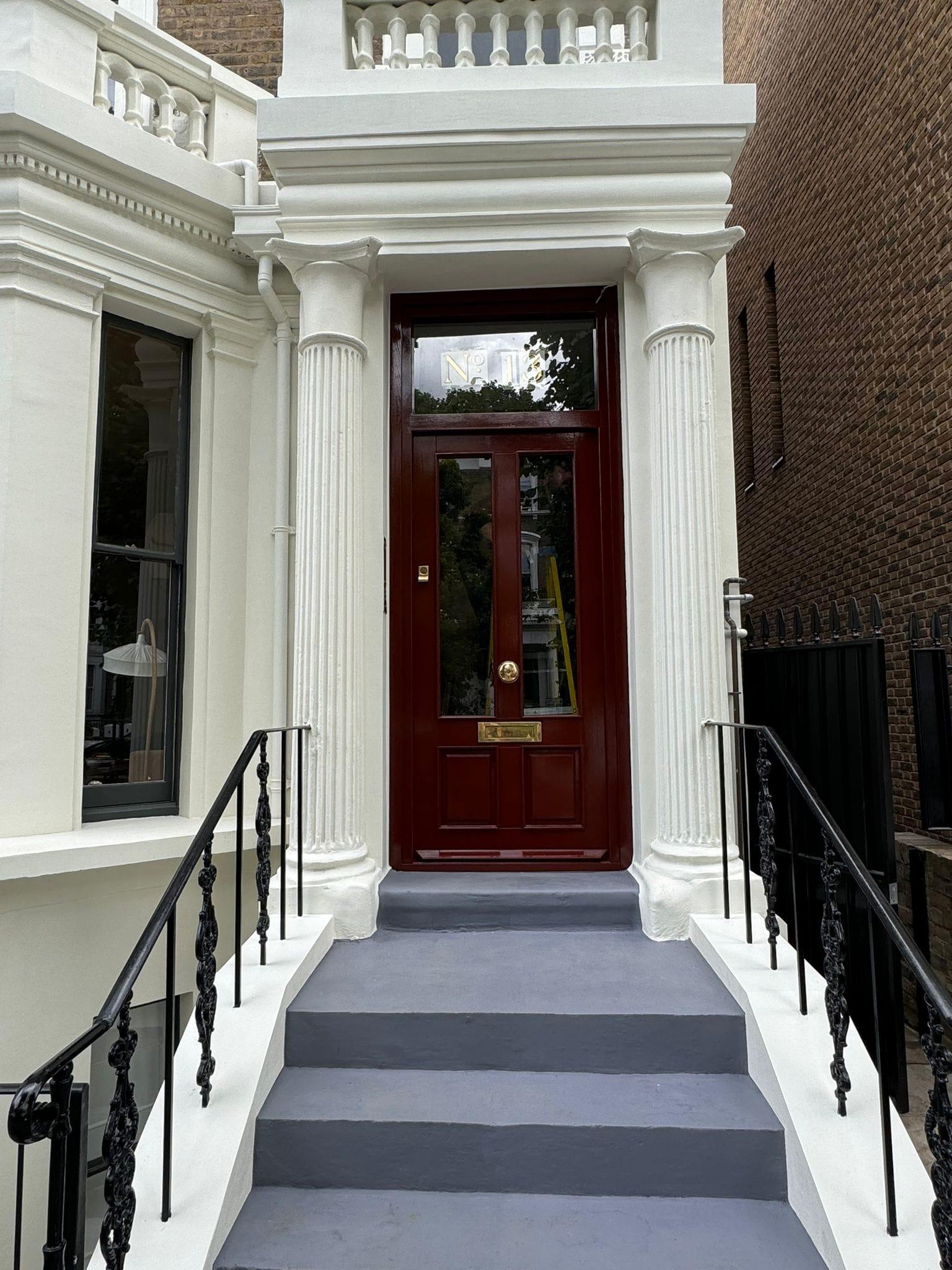 Stuccoed Victorian entrance with columns, a red panelled front door and new stone steps