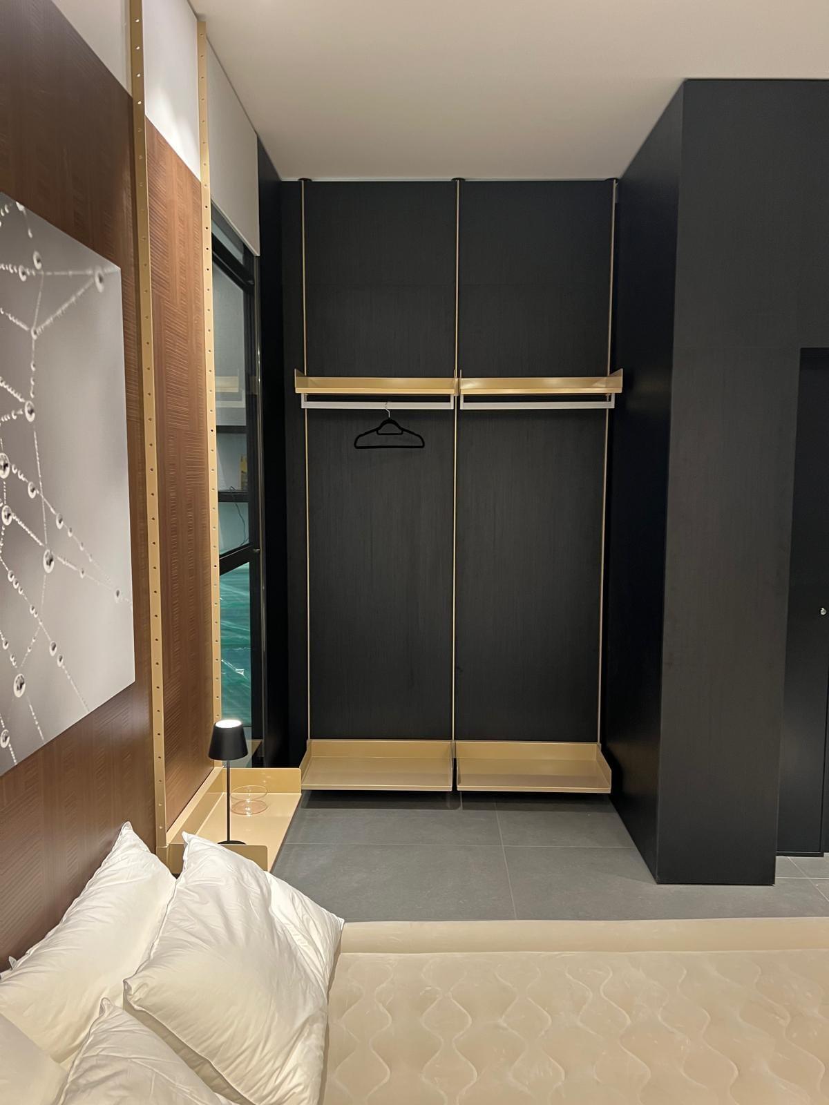 Bedroom with a dark fitted wardrobe, a brass hanging rail and an upholstered headboard