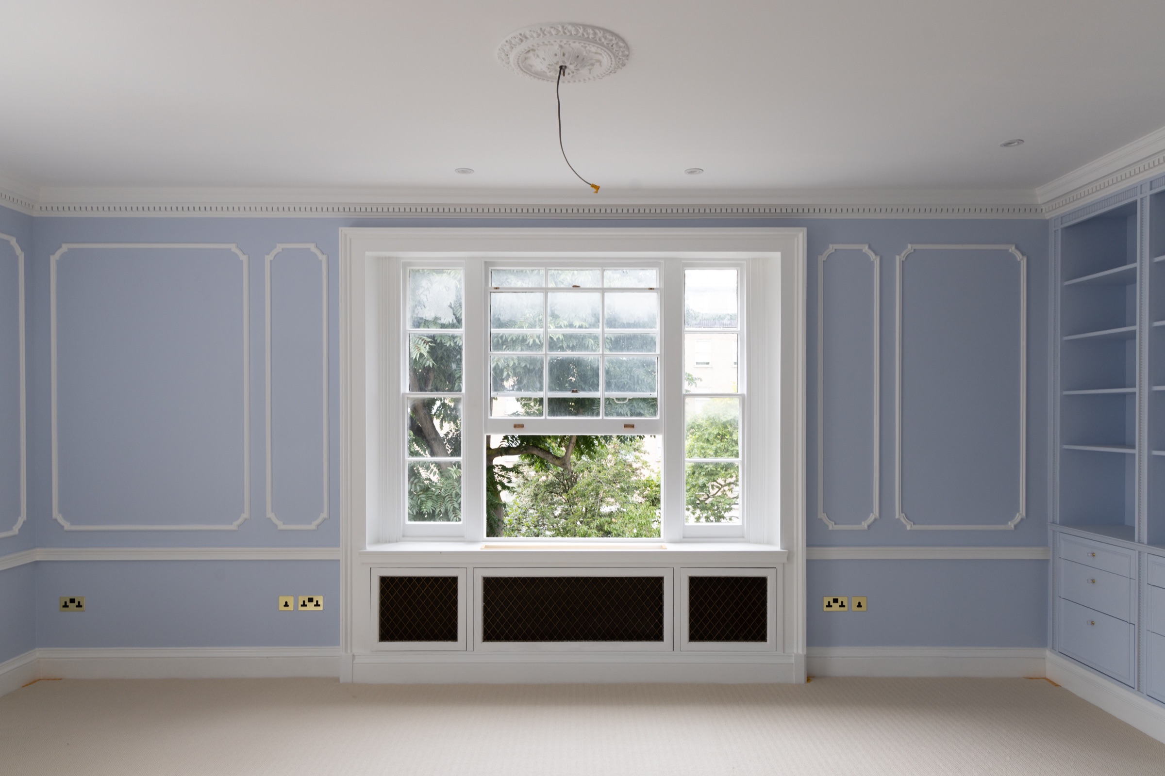 Blue panelled room with white mouldings — Applied panel mouldings, white dado, cornice and ceiling rose, fitted shelving painted to match
