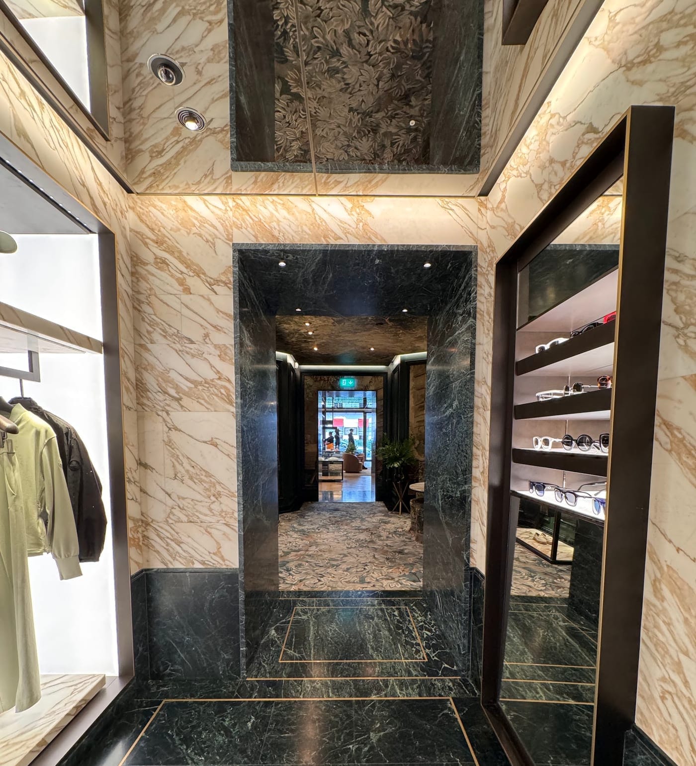 Corridor lined in book-matched marble with lit display cases either side, in a London retail fit-out delivered by 2VP in an operational building