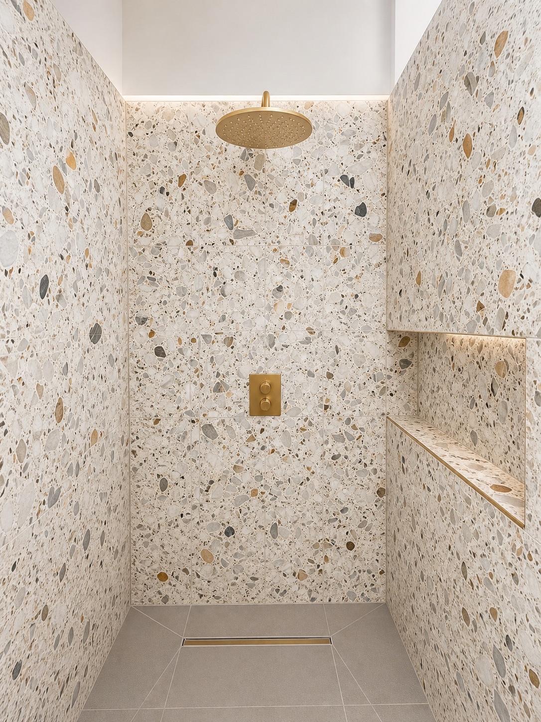 Terrazzo wet room — Fully tanked walk-in shower, linear drain set into the floor falls, brass rain head, lit terrazzo bench and niche
