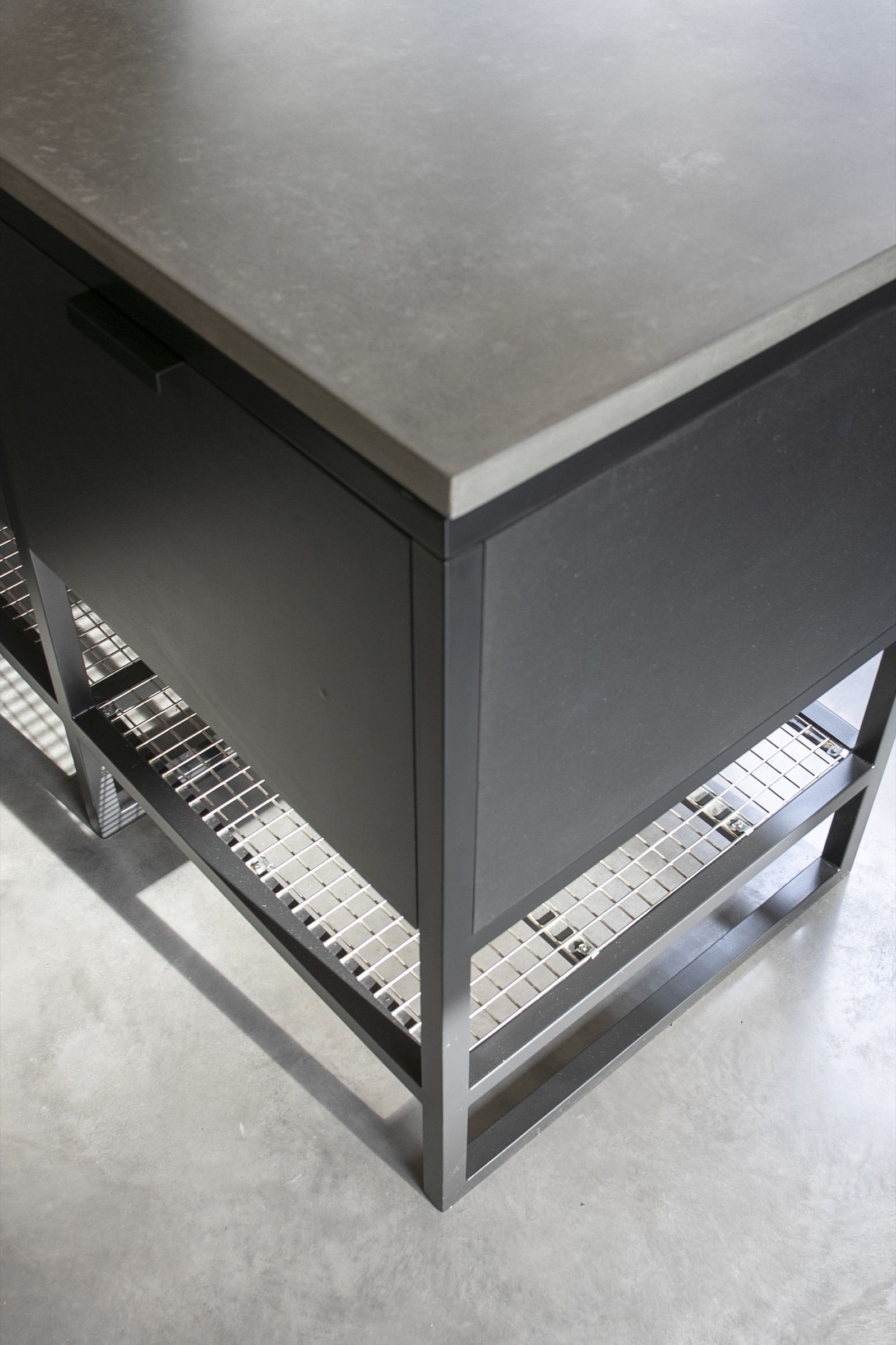 Island and concrete worktop — Poured concrete top with a shadow-gap reveal, handleless carcasses, integrated hob run